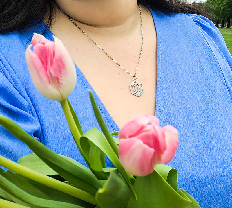 Woman in blue dress wearing stainless steel tulip necklace, holding a bouquet of tulips