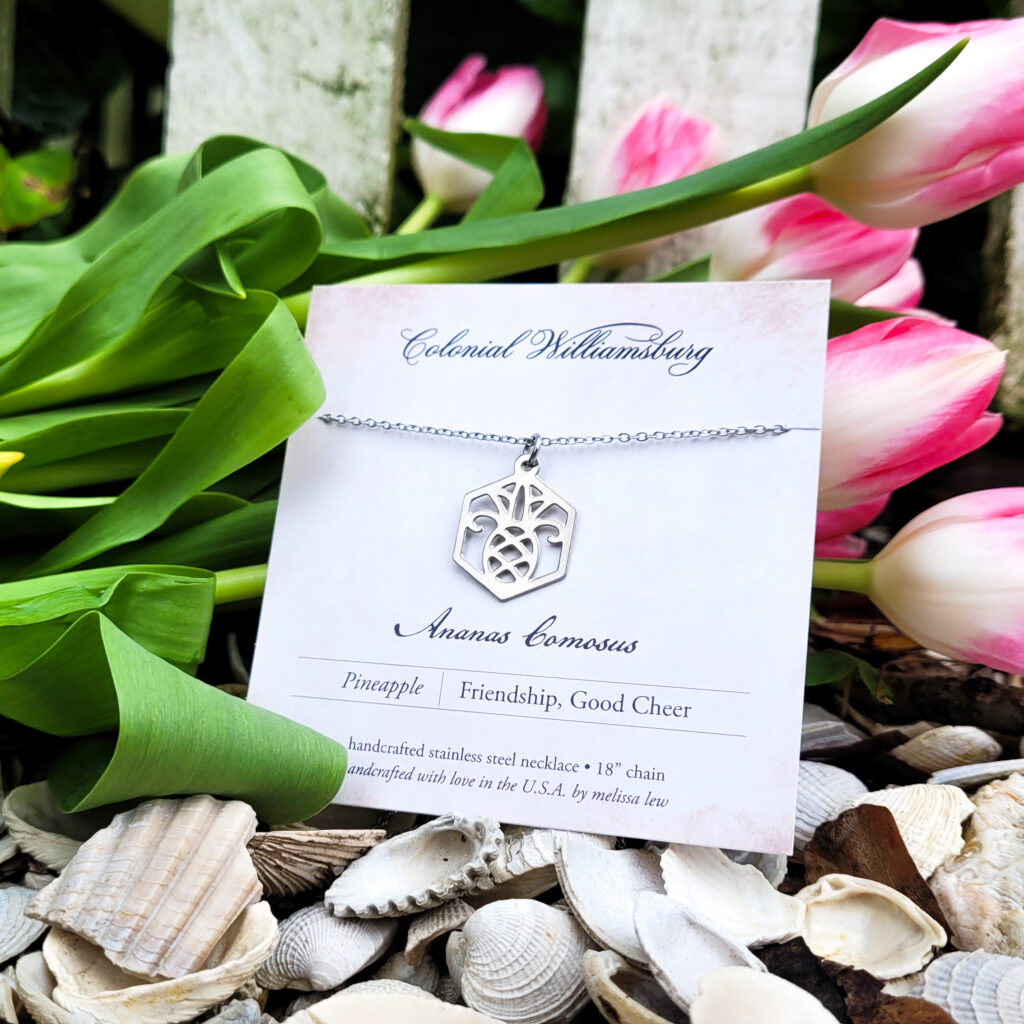 Stainless steel pineapple hexagonal pendant on chain surrounded by tulips