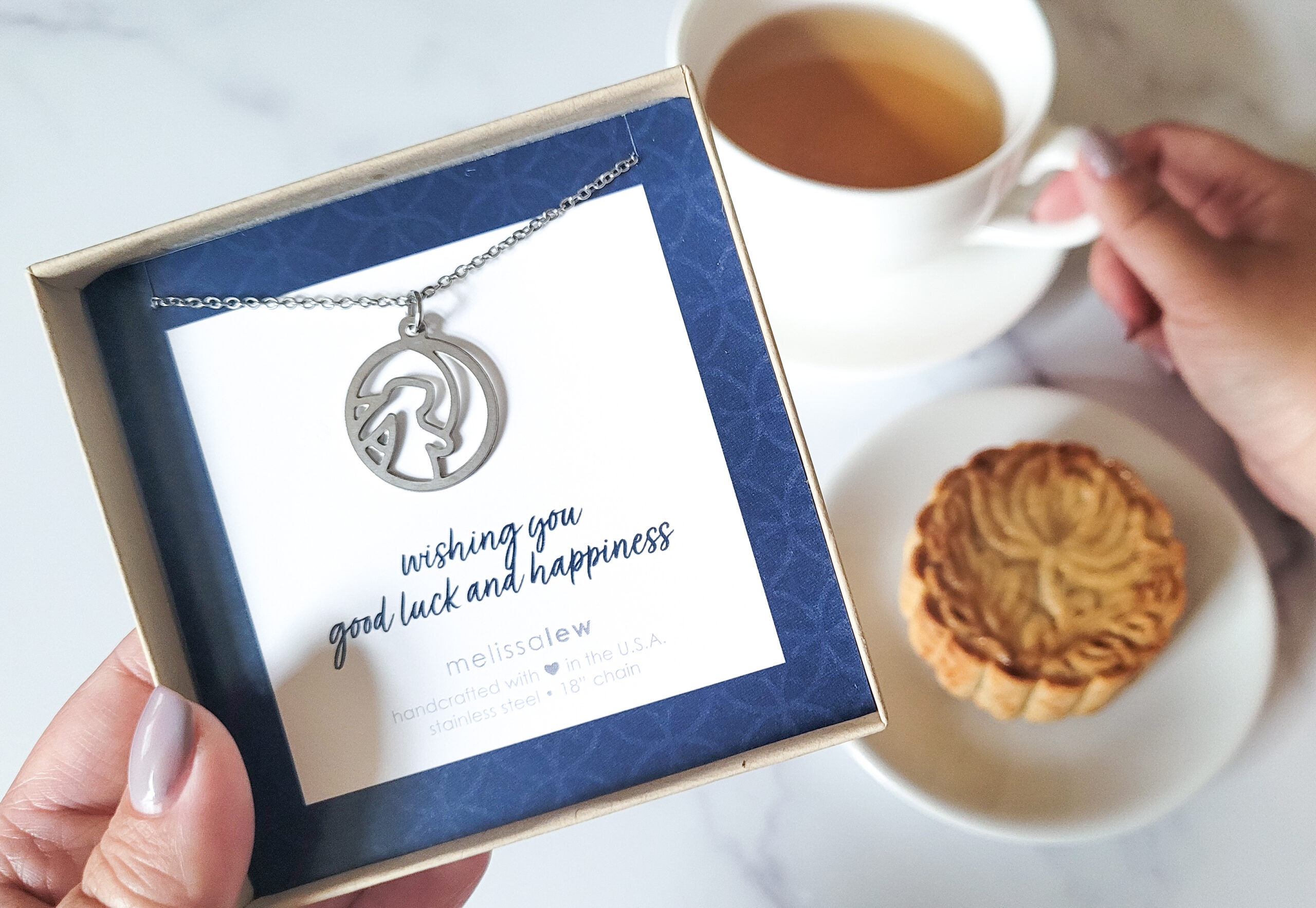 Mooncake with tea, artist holding moon rabbit necklace