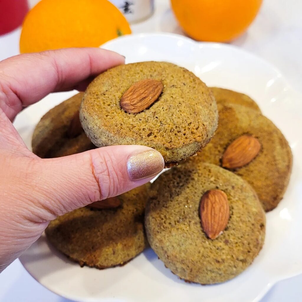 Picking up a round matcha almond cookie with an almond on top